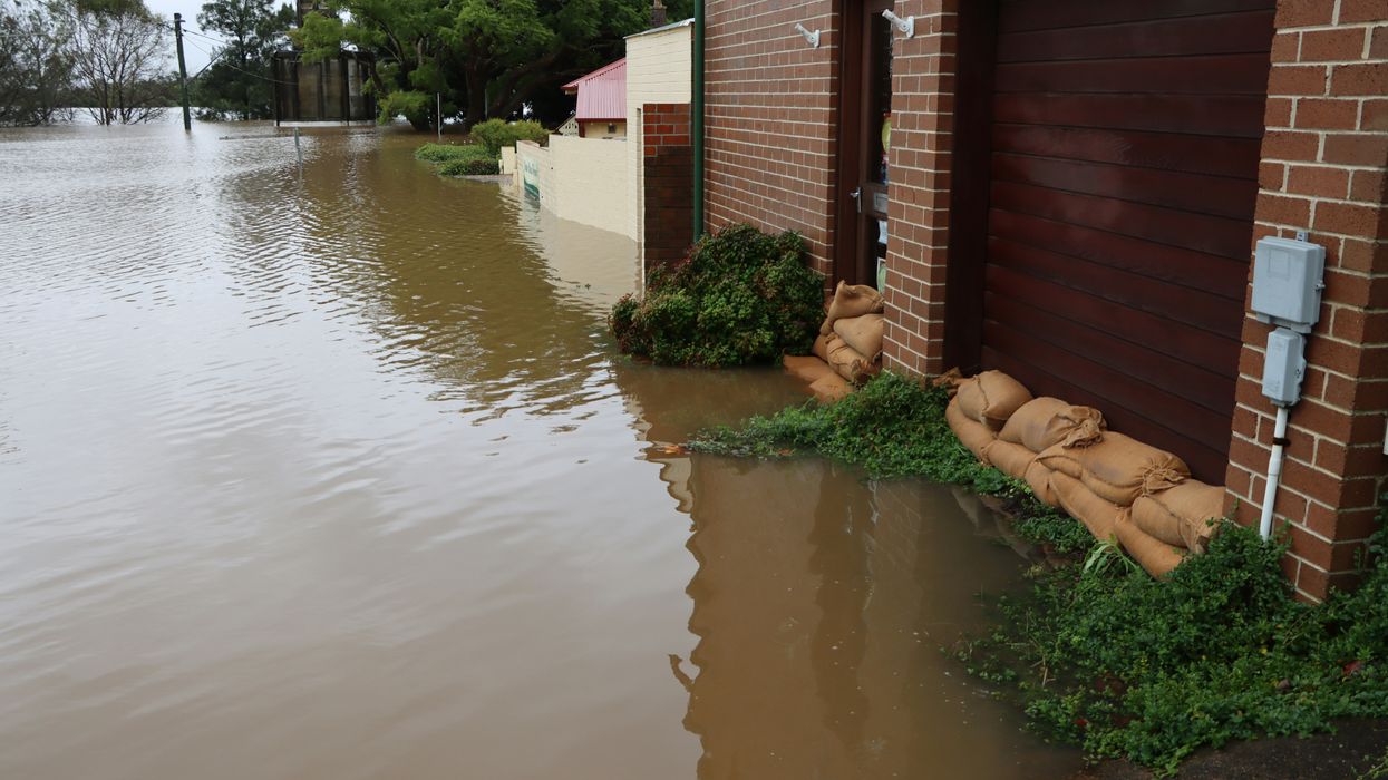 A flooded street with a building and sandbags protecting the doors.