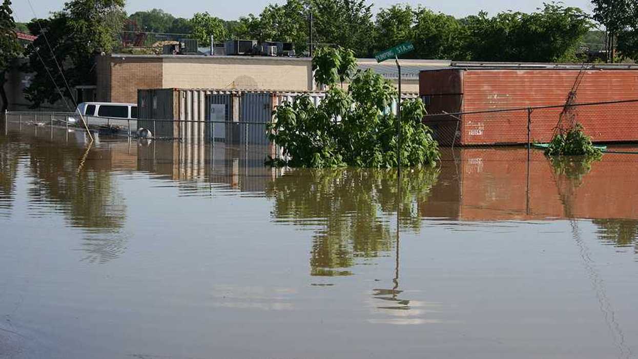 A flooded street with building and a van submerged