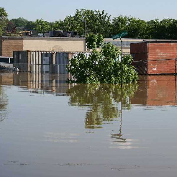 A flooded street with building and a van submerged