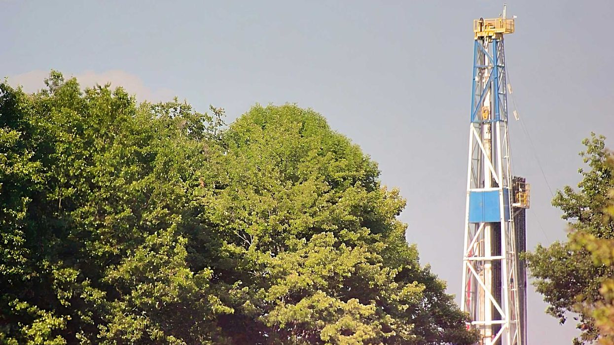 A fracking rig above a group of trees.