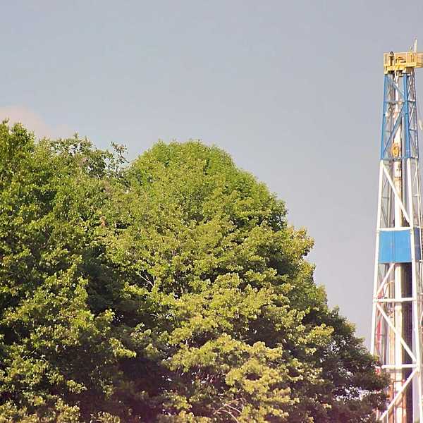 A fracking rig above a group of trees.