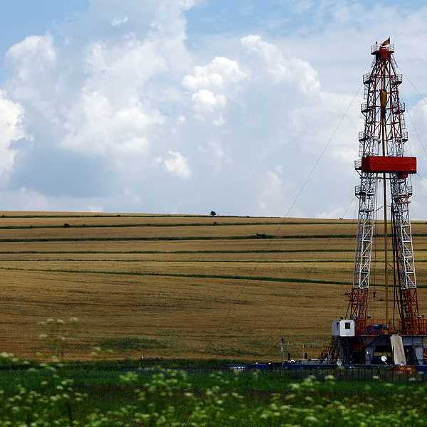 A fracking tower sitting in front of a farm field