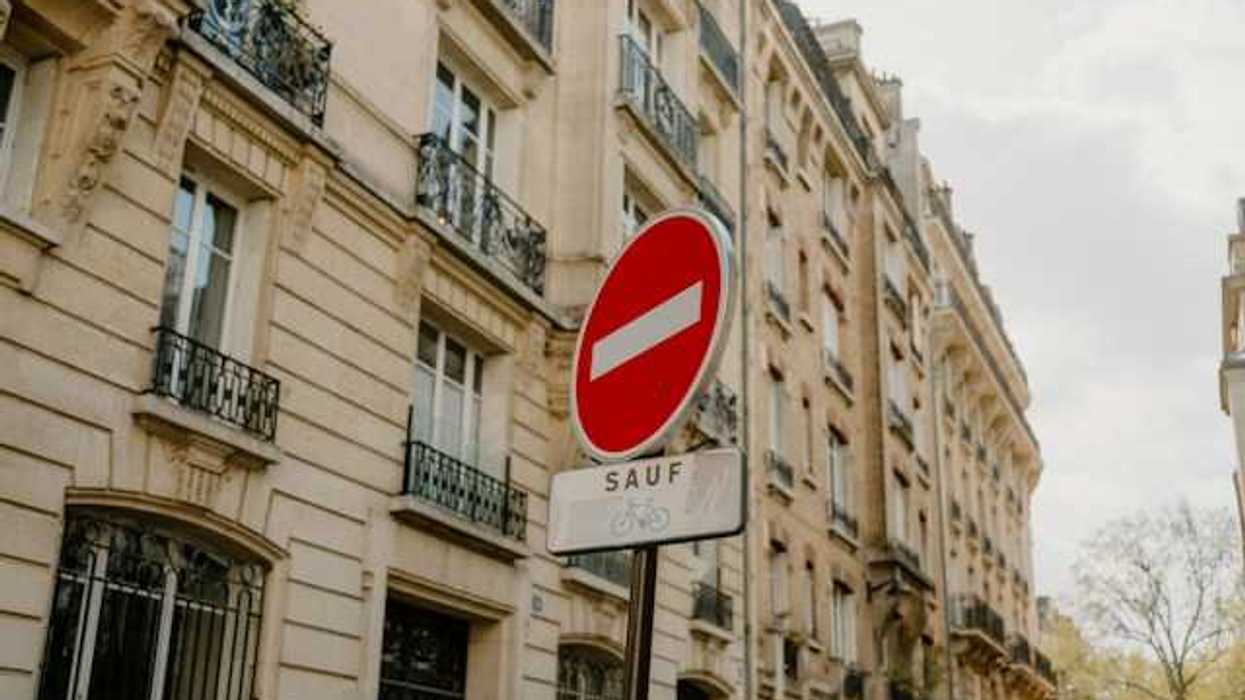 A French sign restricting cars from a street with Parisian buildings in the background