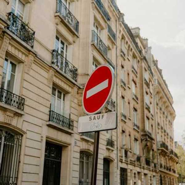 A French sign restricting cars from a street with Parisian buildings in the background