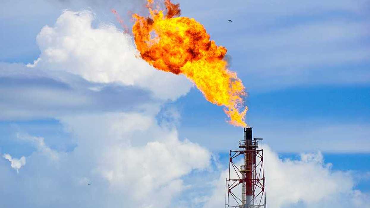 A gas tower flaring orange flames into the sky