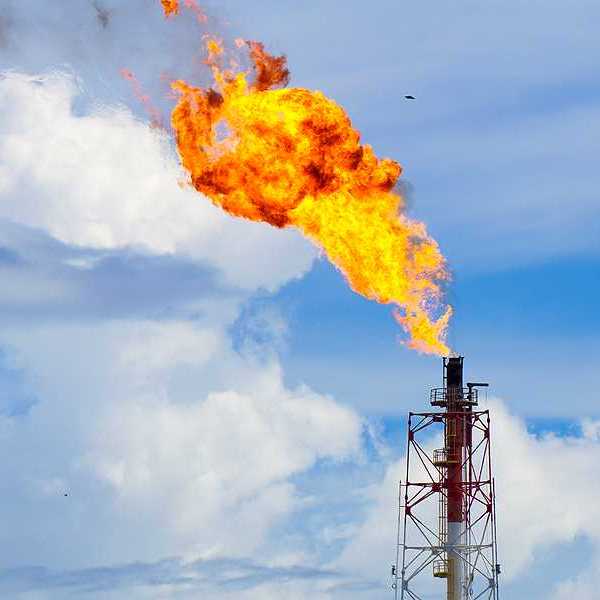 A gas tower flaring orange flames into the sky