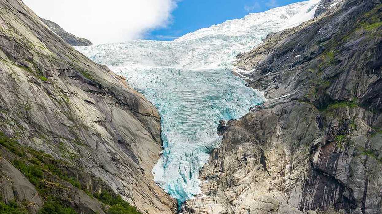 A glacier flowing down between two dry rocky ridges