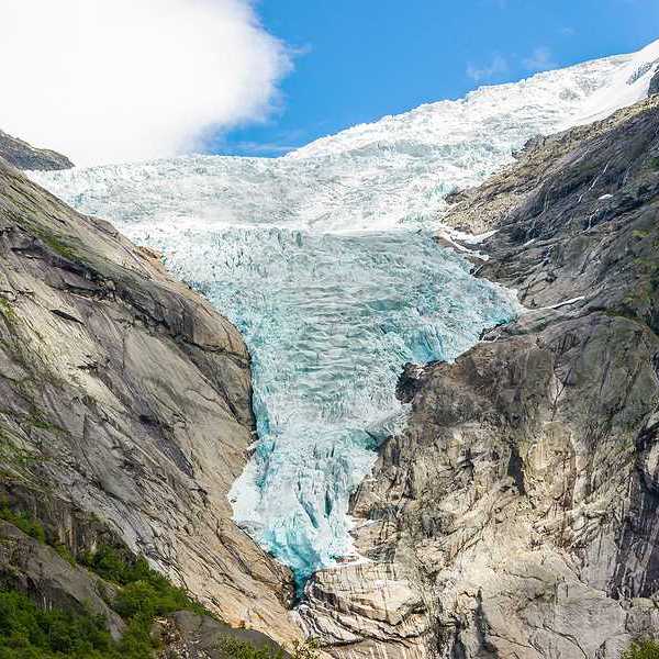 A glacier flowing down between two dry rocky ridges