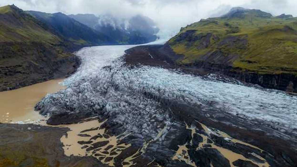 A glacier shown between two low mountain ranges
