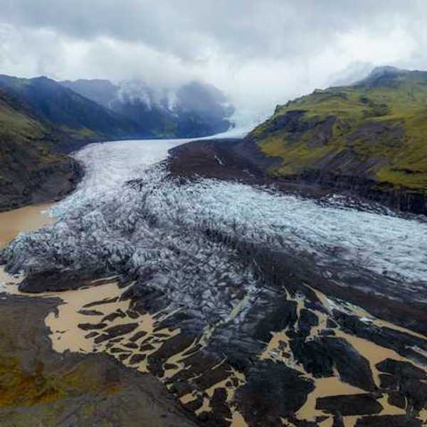 A glacier shown between two low mountain ranges