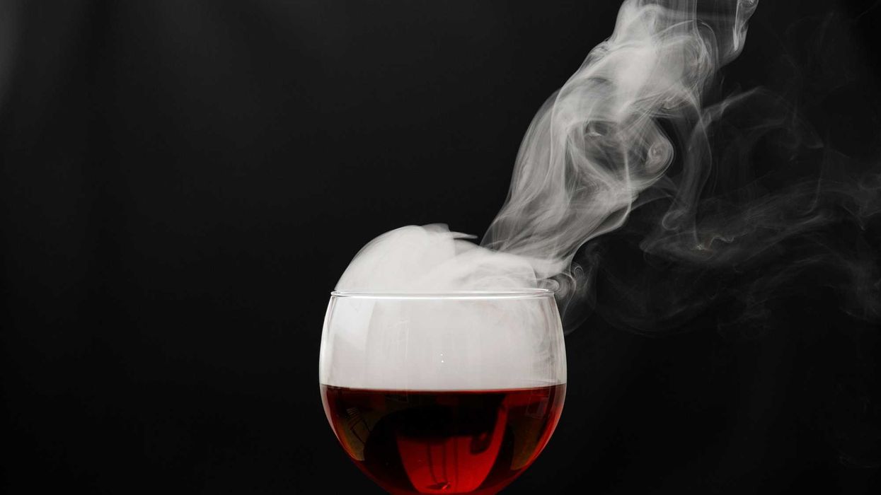 a glass of wine with smoke coming out of it