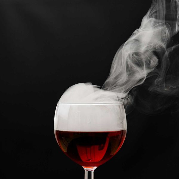 a glass of wine with smoke coming out of it