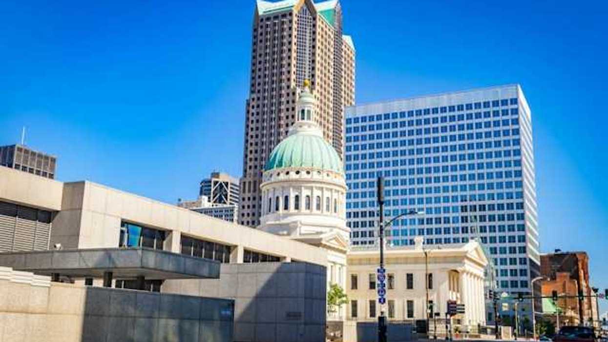 A government building in a downtown area with a tall building in the background