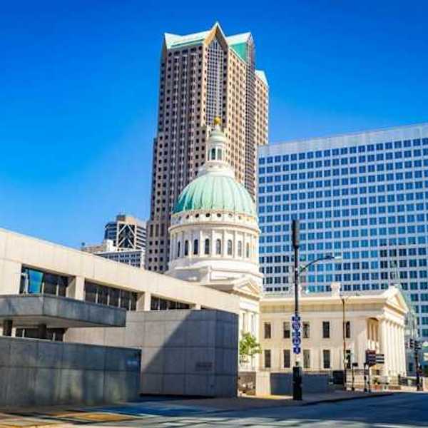 A government building in a downtown area with a tall building in the background