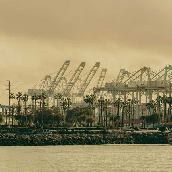 A grayscale photo of the Long Beach port with cranes in the distance