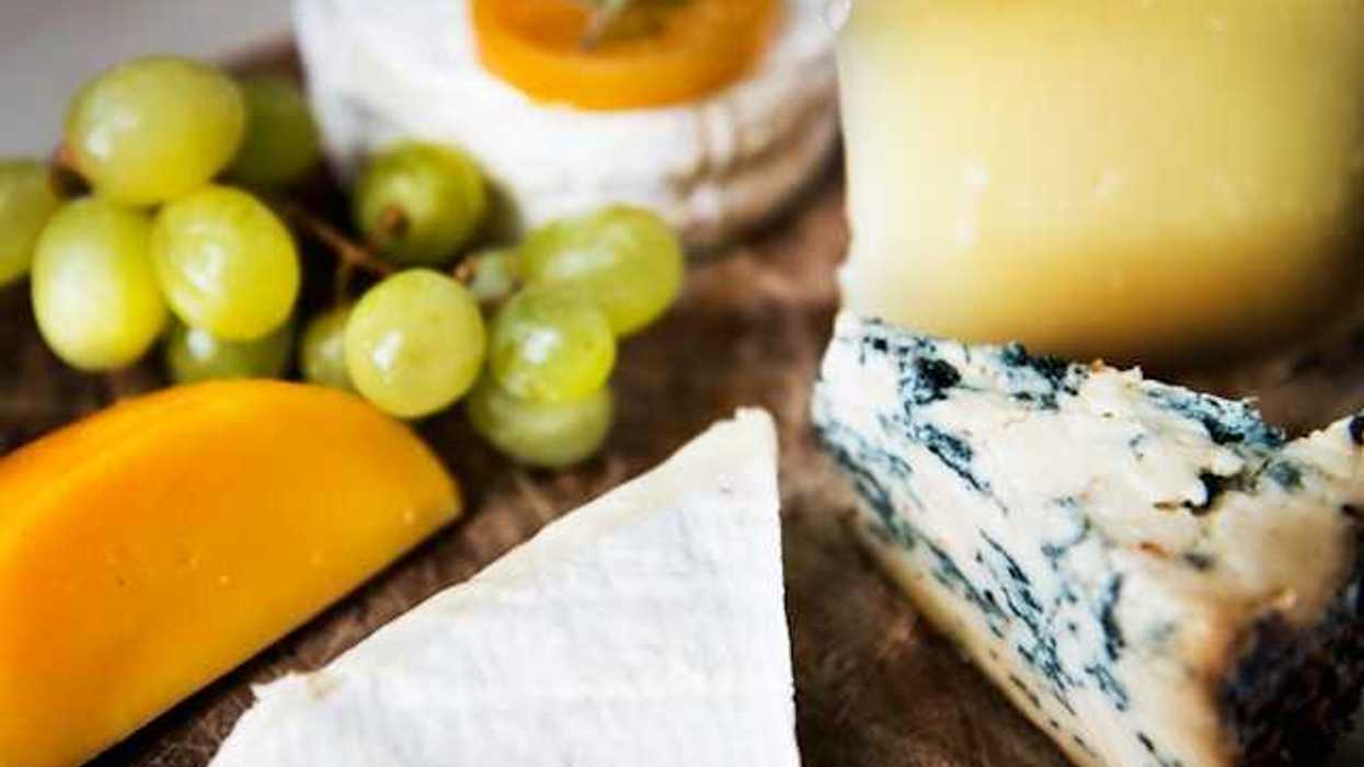 A group of cheese and grapes on a wooden board