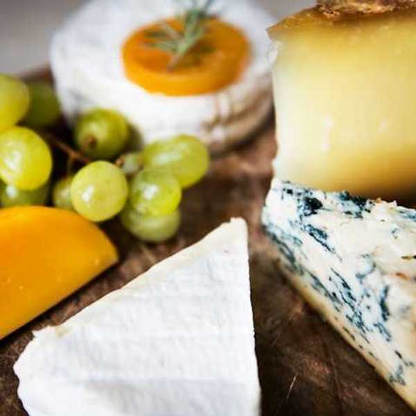 A group of cheese and grapes on a wooden board