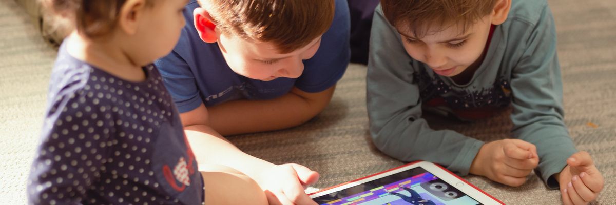 A group of children play on an iPad