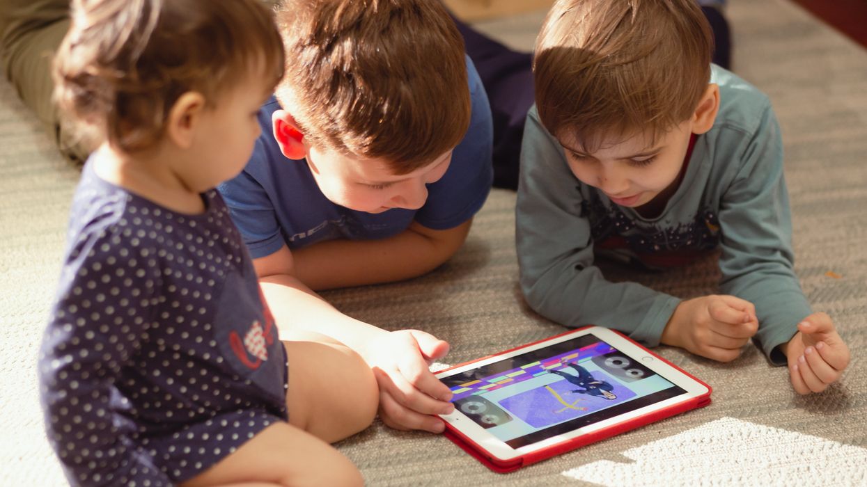 A group of children play on an iPad