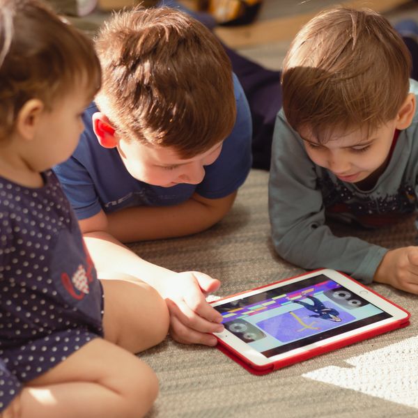 A group of children play on an iPad