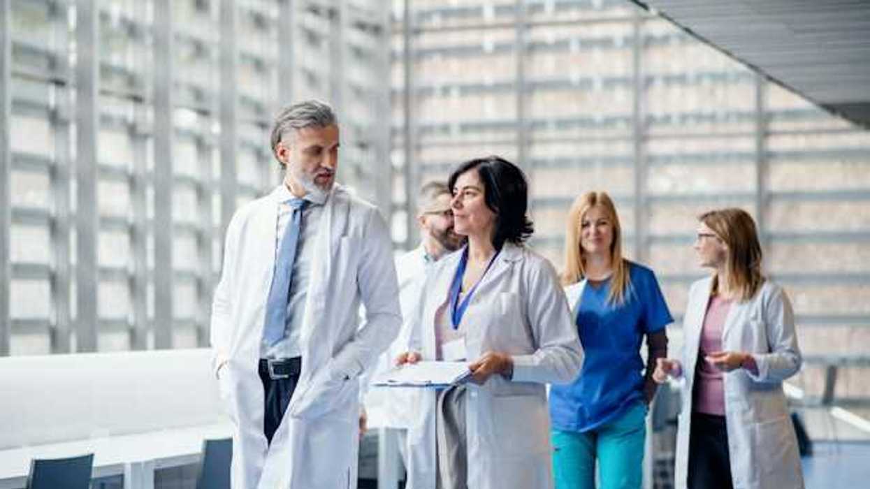 A group of doctors and nurses walking along a hospital hallway