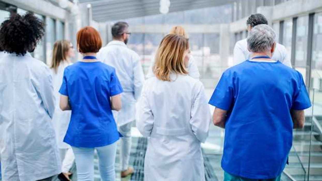 A group of doctors walking down a hallway in a hospital