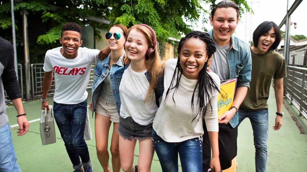 A group of enthusiastic teenagers wallking with arms around one another