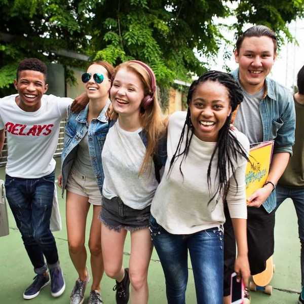 A group of enthusiastic teenagers wallking with arms around one another