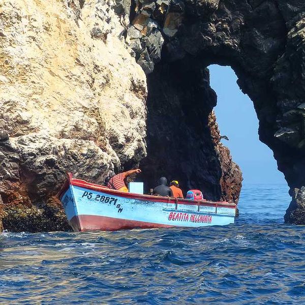A group of fishermen in a boat on the water near rocks