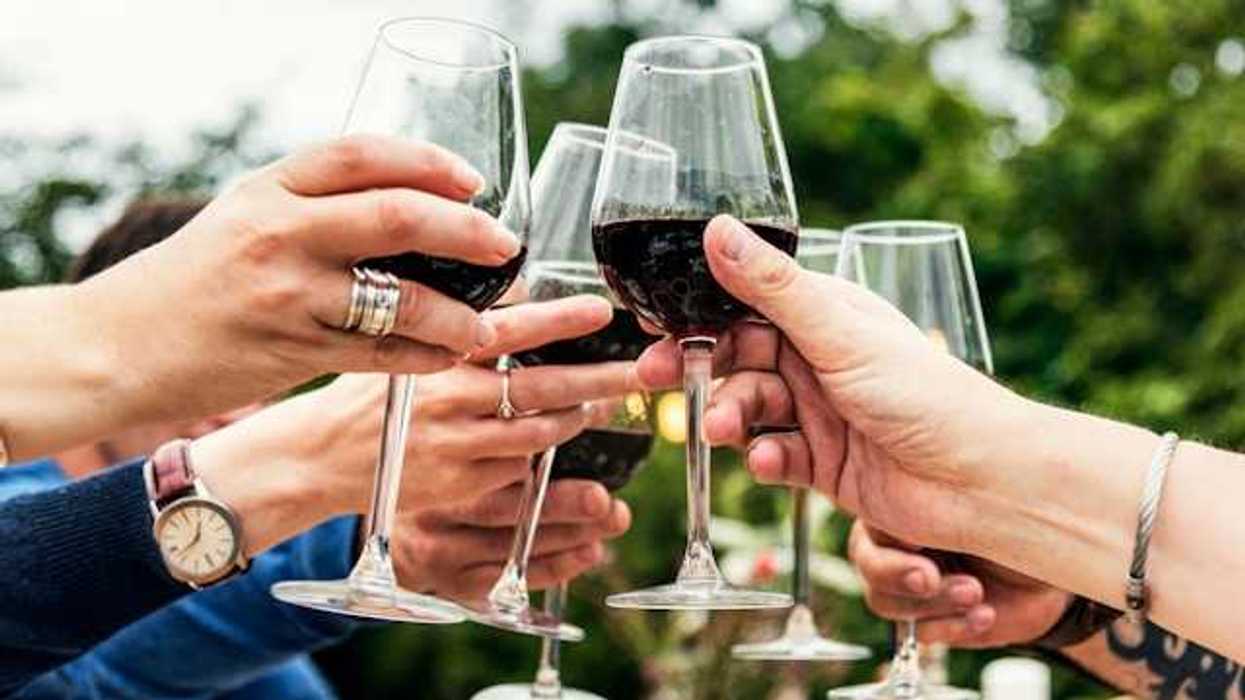 A group of hands holding wine glasses in a toast