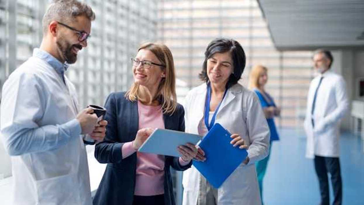 A group of hospital staff and administrators discussing something in a hallway