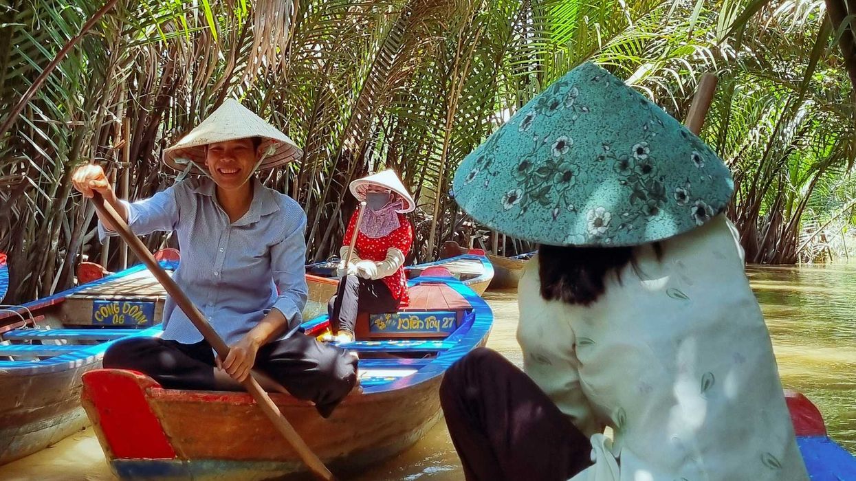 A group of people in hats riding on top of small rowboats on a river.