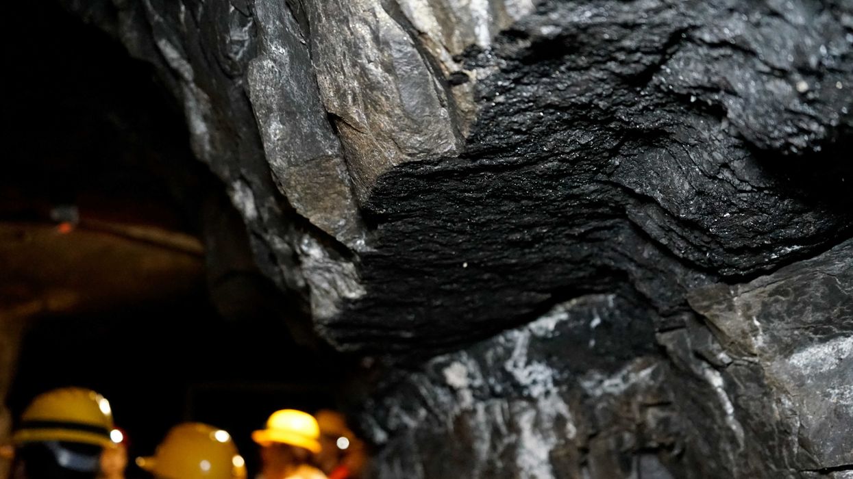 a group of people in yellow hard hats standing in a coal mine.