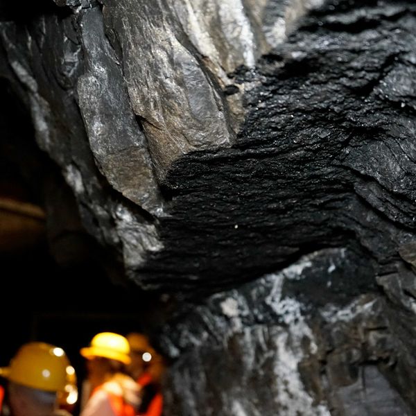 a group of people in yellow hard hats standing in a coal mine.