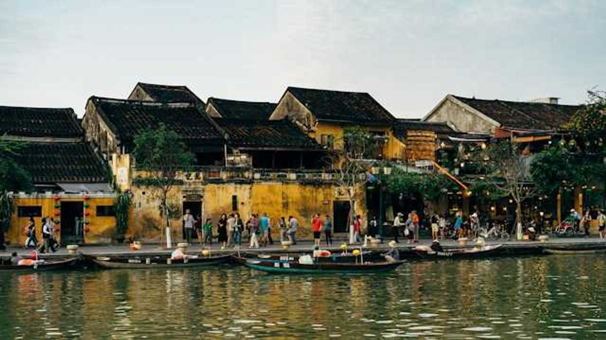 A group of people on a pier standing next to a body of water with small boats