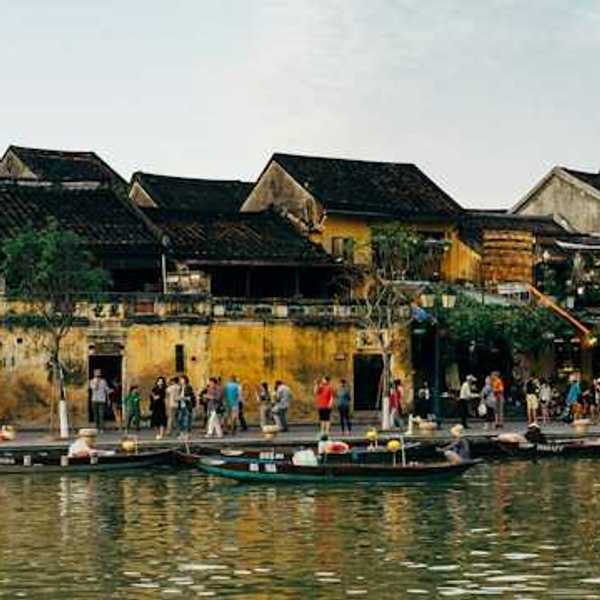 A group of people on a pier standing next to a body of water with small boats