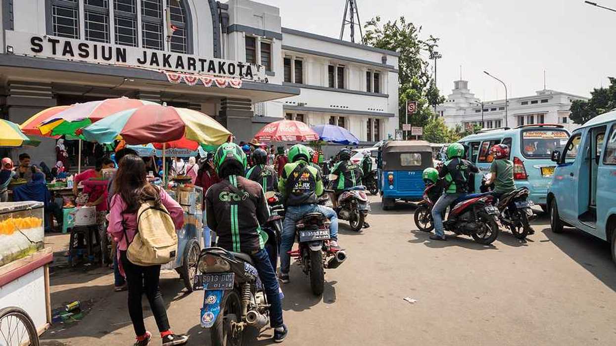 A group of people on motorbikes outside a Jakarta train station