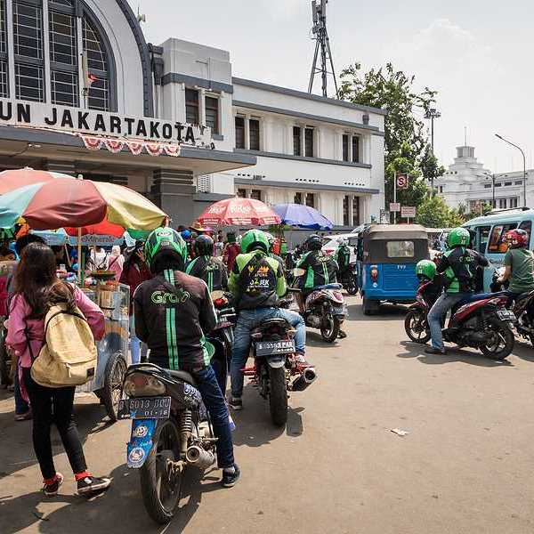 A group of people on motorbikes outside a Jakarta train station