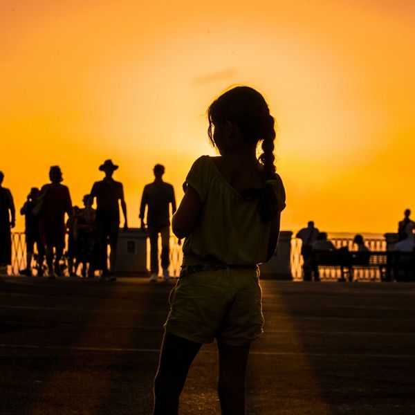 A group of people silhouetted against an orange sun-tinged sky