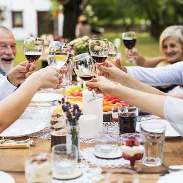 A group of people sitting at an outside table holding glasses of wine