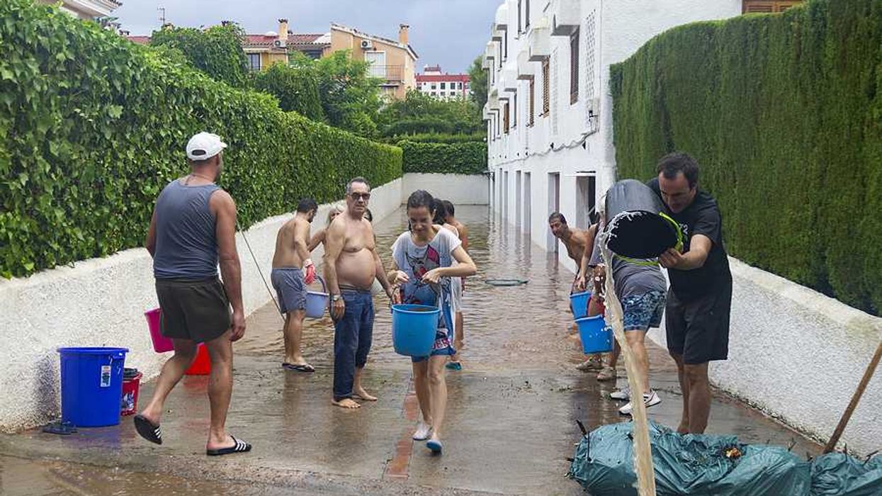 A group of people with buckets trying to carry water from a flooded apartment building