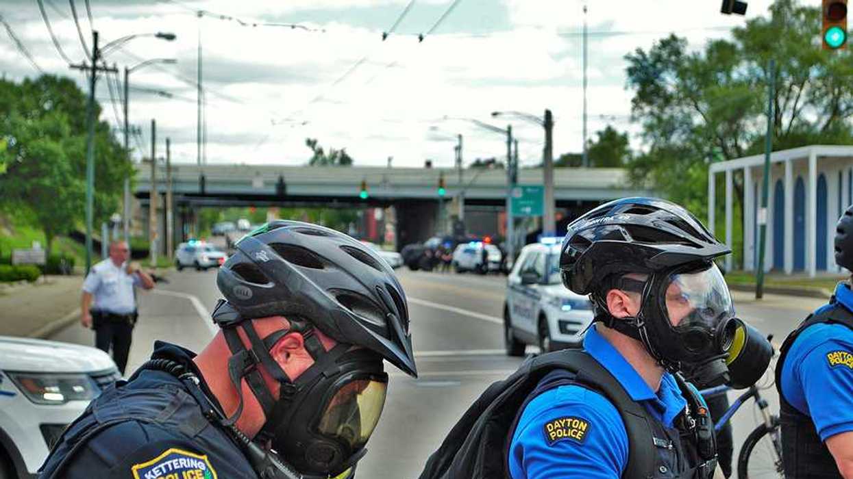 A group of police officers wearing tear gas masks on a city street during daytime