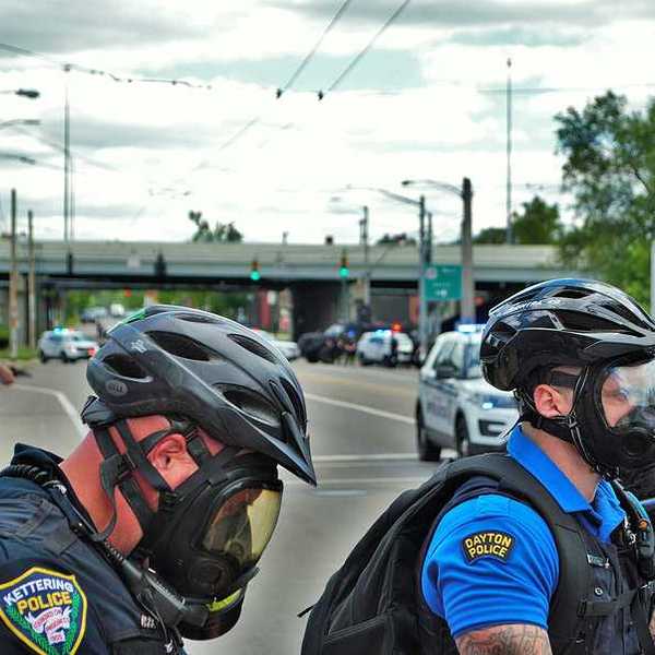 A group of police officers wearing tear gas masks on a city street during daytime