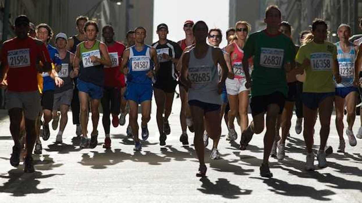 A group of runners with numbered tags running on a city street