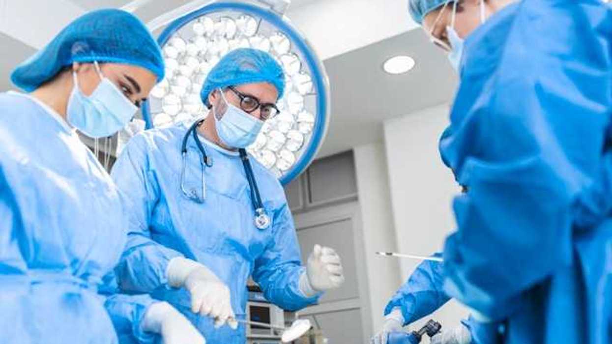 A group of surgeons standing over a patient receiving anesthesia