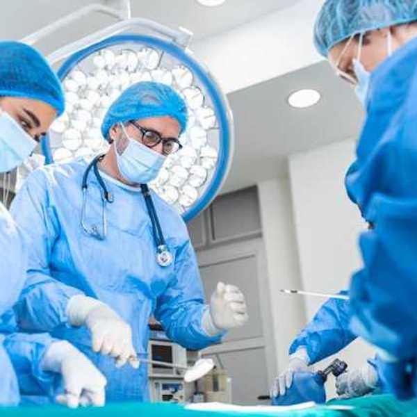 A group of surgeons standing over a patient receiving anesthesia