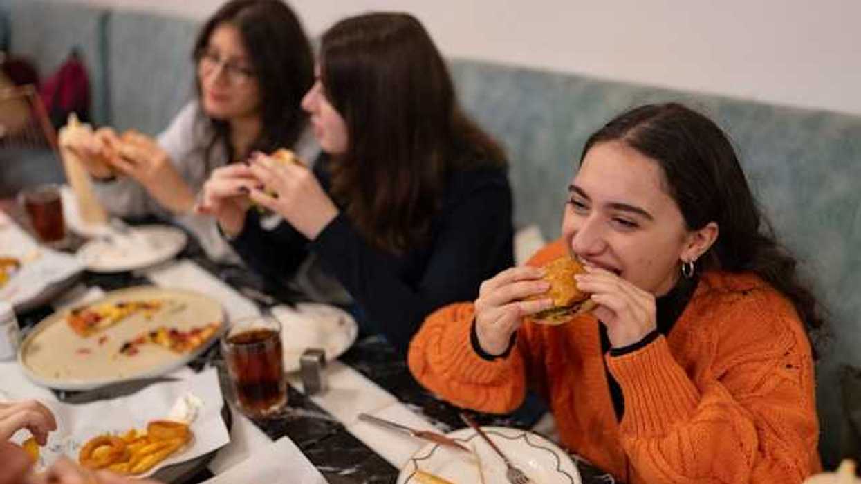 A group of teenage girls eating burgers and pizza