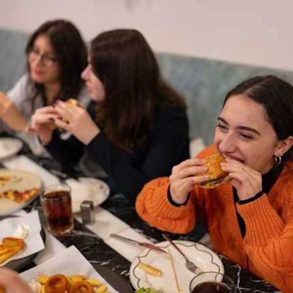 A group of teenage girls eating burgers and pizza