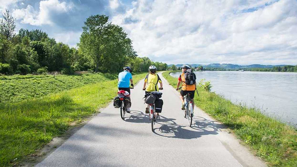 A group of three cyclists bicycling alongside a river