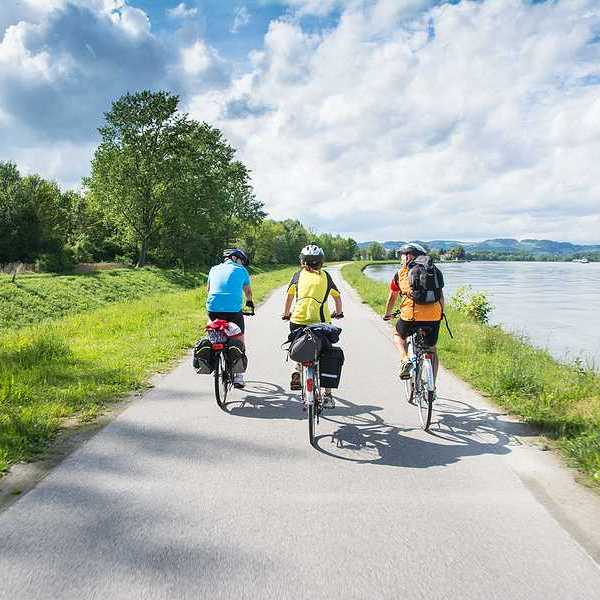 A group of three cyclists bicycling alongside a river